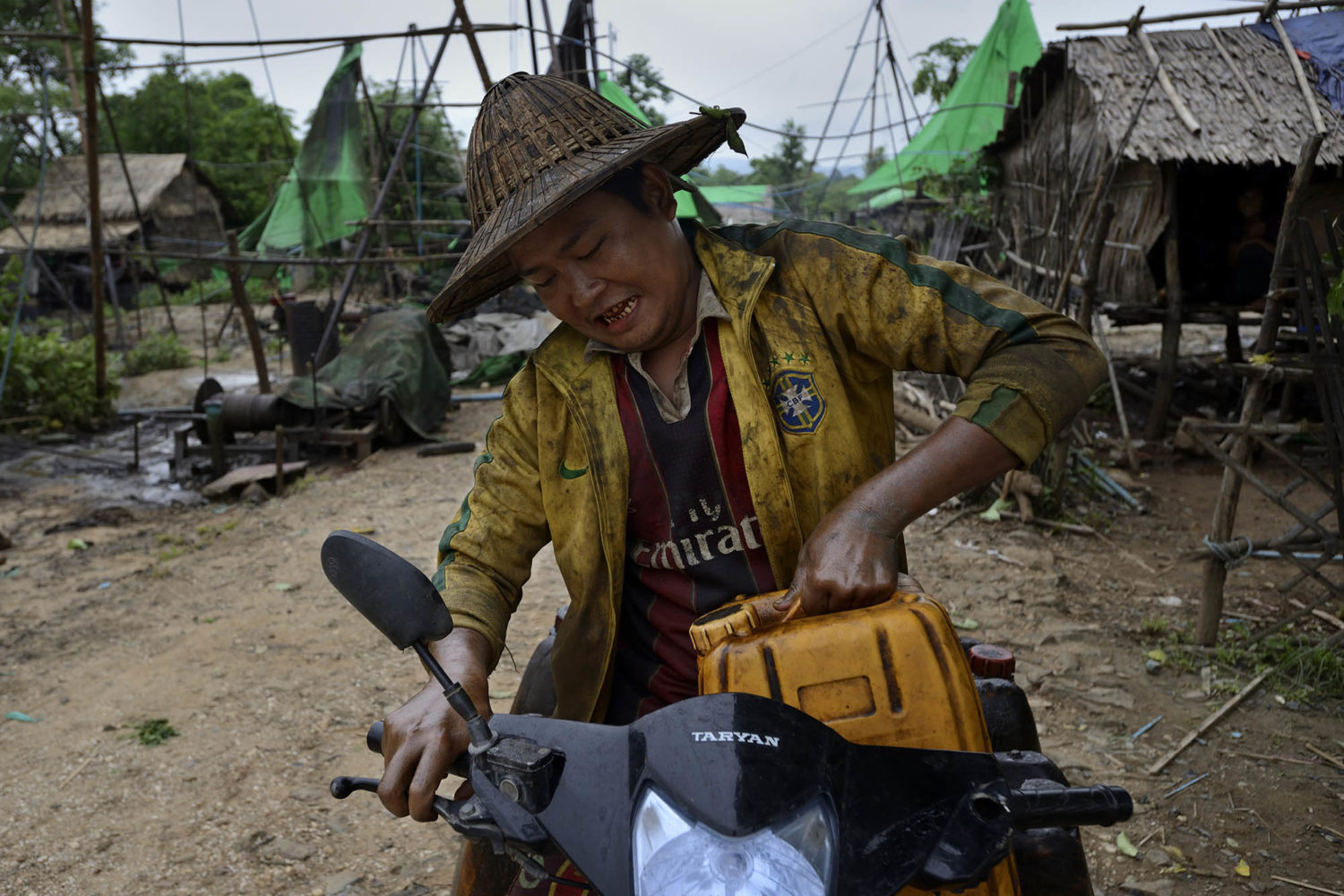 Loading the motor bike with buckets filled with oil, selling for the refineries…
